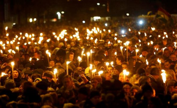 People hold candles during a memorial service is held for those killed on Saturday by a 22-year-old gunman, in Copenhagen February 16, 2015. Danish police said on Monday they had charged two people with aiding the man suspected of shooting dead two people in attacks on a synagogue and an event promoting free speech in Copenhagen at the weekend. The shootings, which Danish Prime Minister Helle Thorning-Schmidt called acts of terrorism, sent shockwaves through Denmark and have been compared to the January attacks in Paris by Islamist militants that killed 17. REUTERS/Hannibal Hanschke 